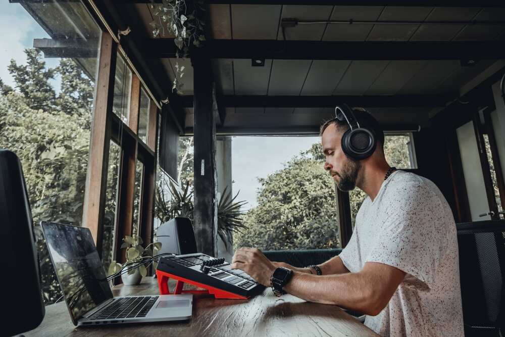 Man producing electronic drum beats on laptop with beat pad.